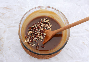 Image showing Stirring chopped pecan nuts into filling for pecan pie