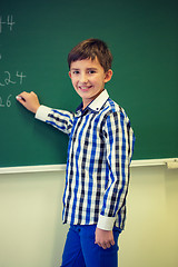 Image showing little smiling schoolboy writing on chalk board