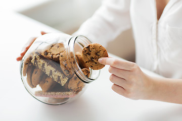 Image showing close up of hands with chocolate cookies in jar