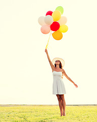 Image showing smiling young woman in sunglasses with balloons