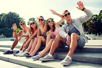 Image showing group of smiling friends sitting on city street