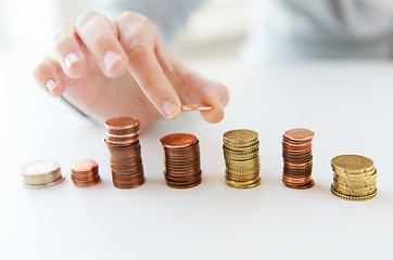 Image showing close up of female hand putting coins into columns