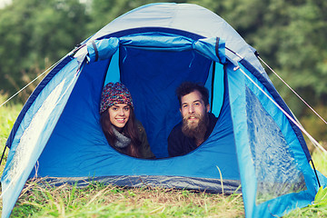 Image showing smiling couple of tourists looking out from tent