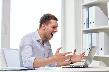 Image showing angry businessman with laptop and papers in office