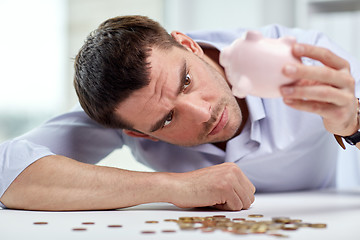 Image showing businessman with piggy bank and coins at office