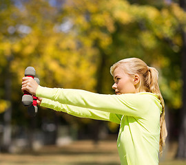 Image showing sporty woman with light dumbbells outdoors