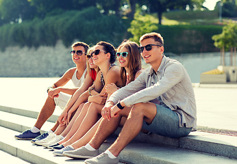 Image showing group of smiling friends sitting on city square