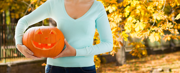 Image showing close up of woman with carved halloween pumpkin