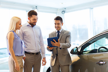 Image showing happy couple with car dealer in auto show or salon