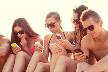 Image showing friends with smartphones on beach