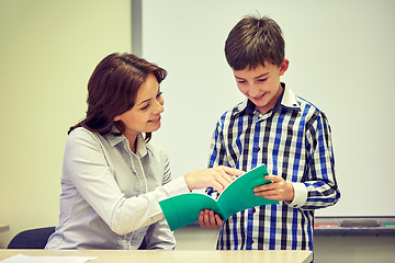 Image showing school boy with notebook and teacher in classroom