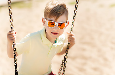 Image showing happy little boy swinging on swing at playground