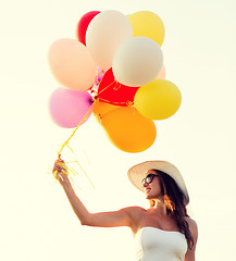 Image showing smiling young woman in sunglasses with balloons