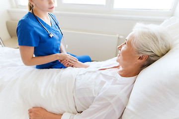 Image showing doctor or nurse visiting senior woman at hospital
