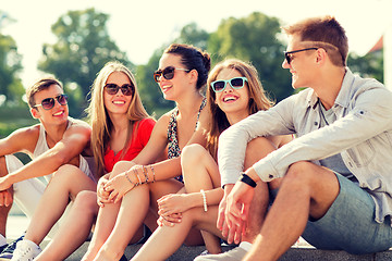 Image showing group of smiling friends sitting on city street