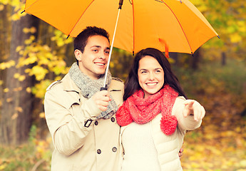 Image showing smiling couple with umbrella in autumn park