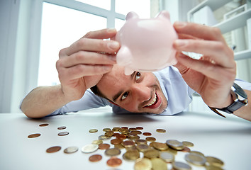 Image showing businessman with piggy bank and coins at office