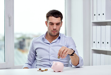 Image showing businessman with piggy bank and coins at office