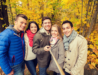 Image showing smiling friends with smartphone in city park