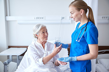 Image showing nurse giving medicine to senior woman at hospital