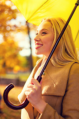 Image showing smiling woman with umbrella in autumn park