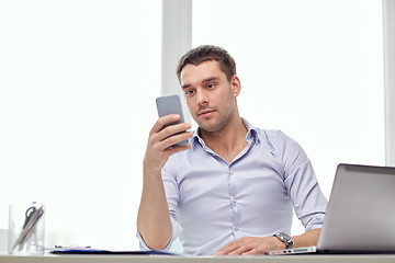 Image showing businessman with smartphone and laptop at office