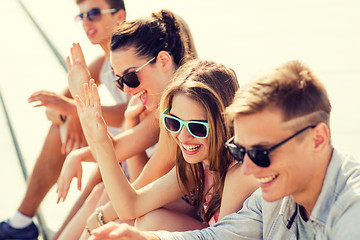 Image showing group of laughing friends sitting on city square