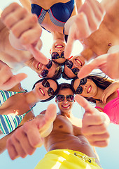 Image showing smiling friends showing thumbs up in circle