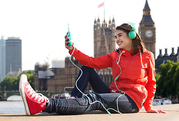 Image showing happy young woman with smartphone and headphones