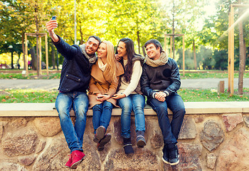 Image showing smiling friends with smartphones in city park