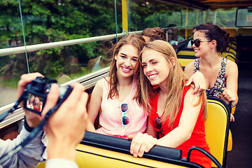 Image showing smiling friends with camera traveling by tour bus