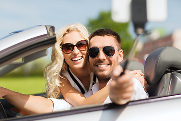 Image showing happy couple in car taking selfie with smartphone