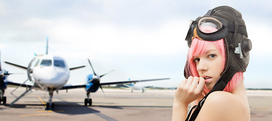 Image showing girl in aviator helmet over plane at airport