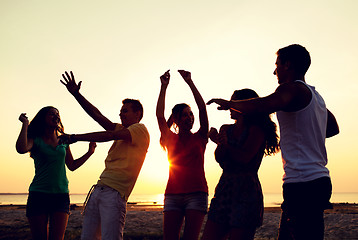 Image showing smiling friends dancing on summer beach