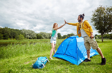 Image showing happy couple setting up tent outdoors