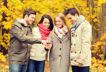 Image showing smiling friends with smartphones in city park