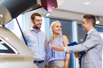 Image showing happy couple with car dealer in auto show or salon