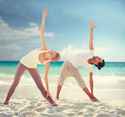 Image showing couple making yoga exercises on summer beach