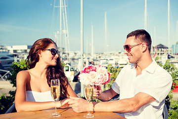 Image showing smiling couple with bunch and champagne at cafe