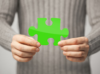 Image showing close up of man holding green puzzle piece