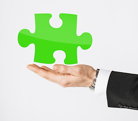 Image showing close up of man holding green puzzle piece