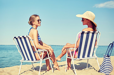 Image showing happy women sunbathing in lounges on beach