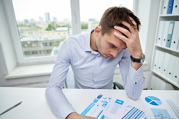 Image showing stressed businessman with papers in office
