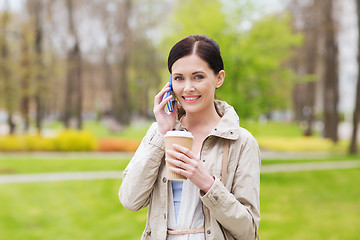 Image showing smiling woman with smartphone and coffee in park