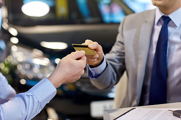 Image showing customer giving credit card to car dealer in salon