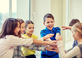 Image showing group of smiling school kids putting hands on top