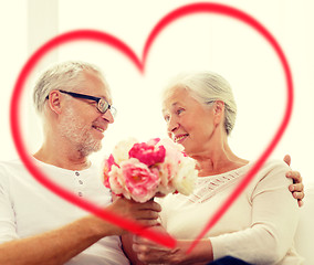 Image showing happy senior couple with bunch of flowers at home