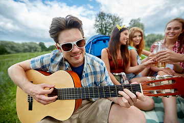 Image showing happy man with friends playing guitar at camping