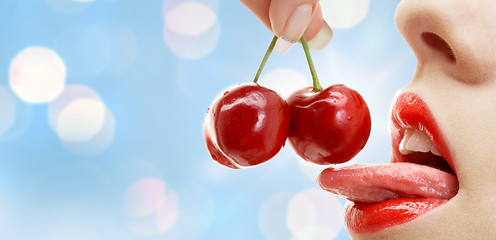 Image showing woman mouth with lips and tongue eating cherry