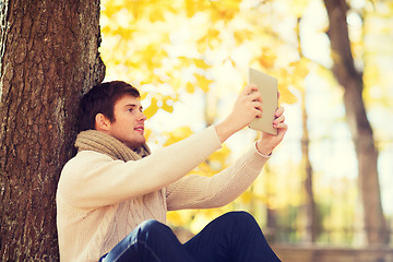 Image showing smiling young man with tablet pc in autumn park